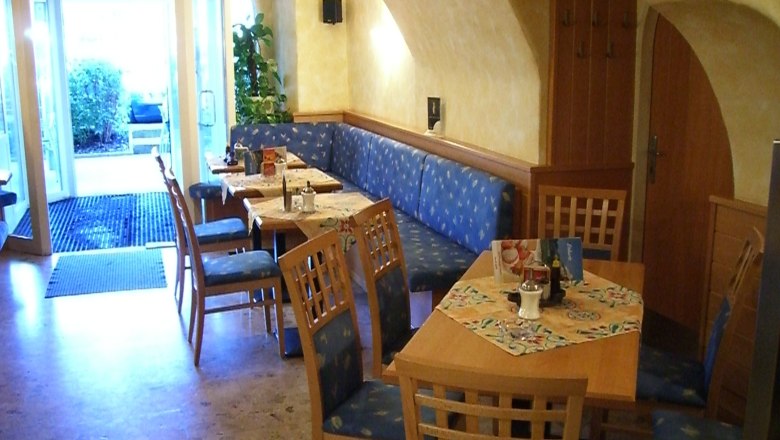 Cafe, © Hotel Anker Innenansicht eines gemütlichen Cafés mit Holzmöbeln und blauen Polstern.