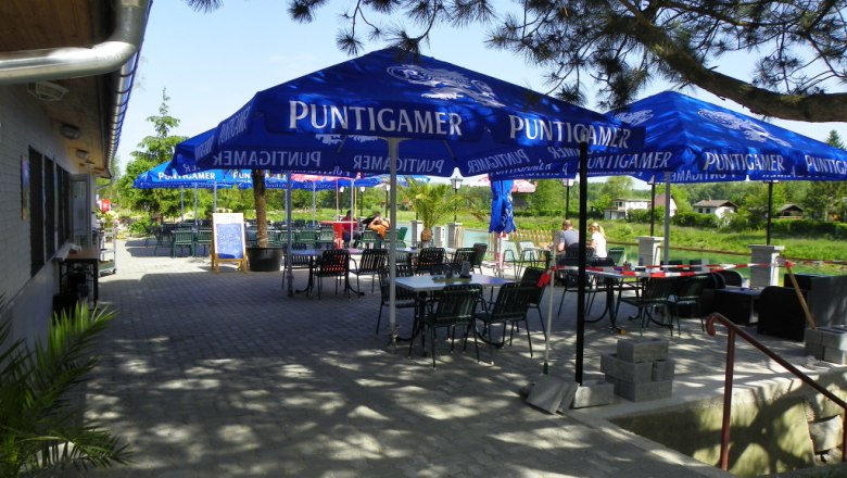 Gasthaus zum Silbersee, © Gasthaus zum Silbersee Außenbereich eines Gasthauses mit blauen Sonnenschirmen und Tischen.