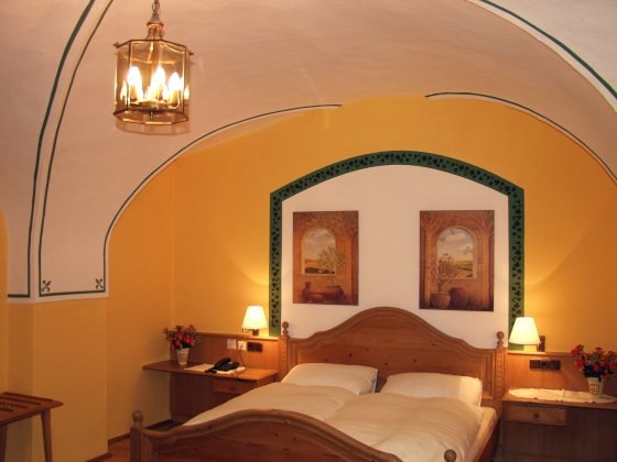 Gemütliches Schlafzimmer mit Holzbett, gelben Wänden und gewölbter Decke.