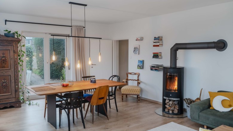 Modernes Wohnzimmer mit Esstisch, St&uuml;hlen, Kamin und B&uuml;cherregalen.