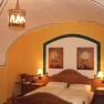 Gemütliches Schlafzimmer mit Holzbett, gelben Wänden und gewölbter Decke.