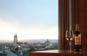 Weinflasche und Glas vor Stadtpanorama mit Kirche.