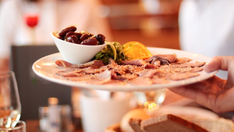 Ein Teller mit Aufschnitt und Oliven wird in einem Restaurant serviert.