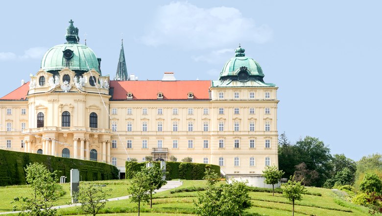 Klosterneuburg Abbey with green domes and well-tended garden in the foreground.