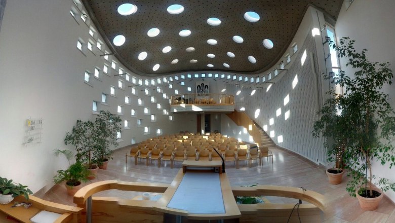Moderner Kircheninnenraum mit runden Fenstern und Holzmöbeln.